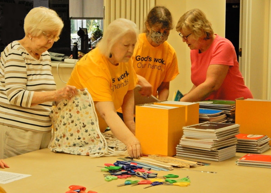 group of people around a table packing school supply bags