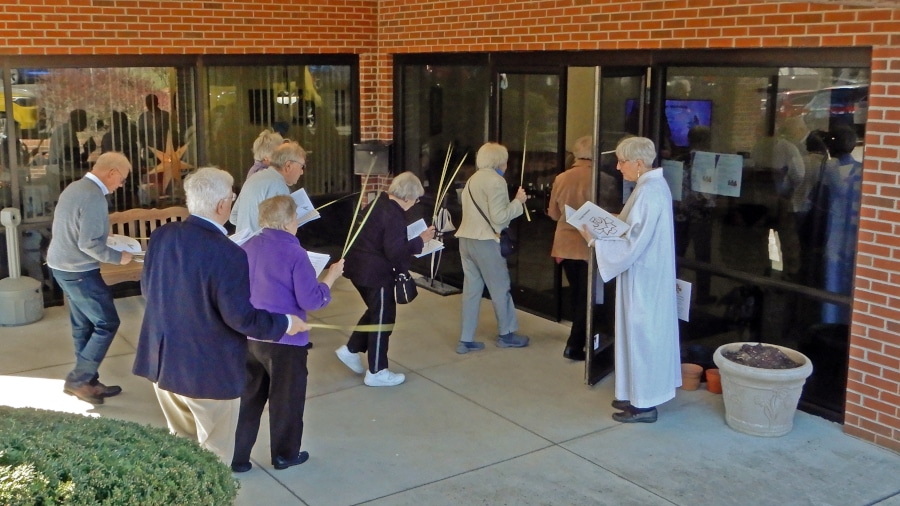 people carrying palm branches walking into a building